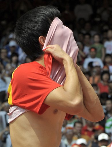 图文-刘翔因伤退出110米栏比赛 用衣服遮住了脸