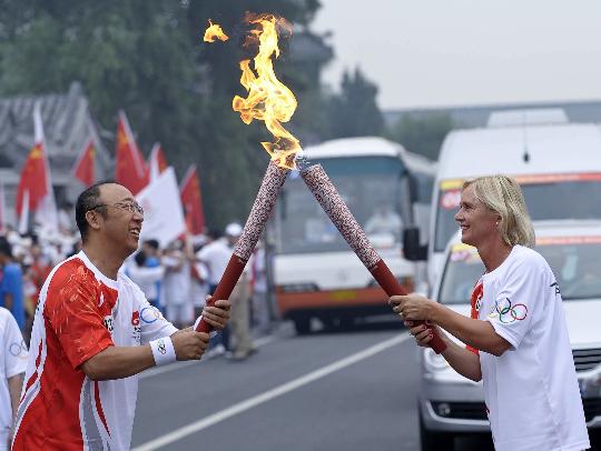 图文-奥运圣火北京首日传递 范美玲与孟令迪交接火炬