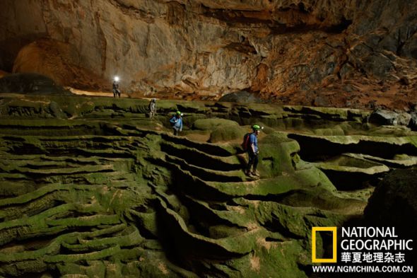 韩松洞里，探险者穿越雕塑般的洞穴地面，行走在苔藓覆盖的迷宫中。