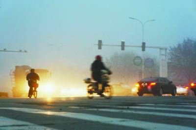 12月5日清晨，在山东聊城市街头，市民在大雾中骑车出行。 