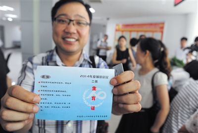 2014年6月17日,河南郑州市金水区行政办事大厅,孙先生领到了单独二孩生育证。图/CFP 2014年6月17日,河南郑州市金水区行政办事大厅,孙先生领到了单独二孩生育证。图/CFP