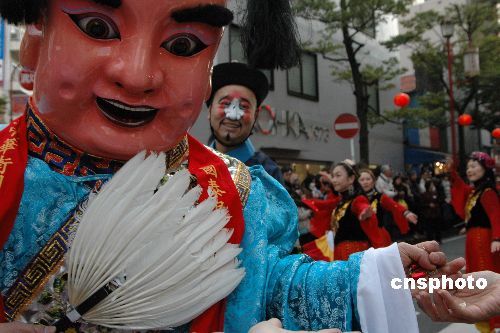 日本横滨中华街举行一年一度的庆新春大游行,吸引众多观众。图为游行队列中的关帝庙进宝童子向观众分发糖果。 日本横滨中华街举行一年一度的庆新春大游行,吸引众多观众。图为游行队列中的关帝庙进宝童子向观众分发糖果。