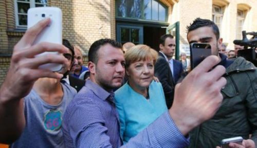 在德国柏林，德国总理默克尔访问难民安置所时与多名难民合影