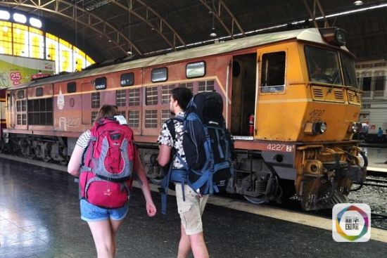 曼谷市火车站，两名游客从老旧的列车旁走过。（新华社发）