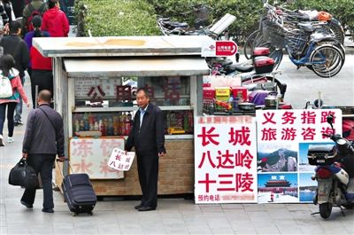 9月30日，北京站附近，一家公共电话亭前摆着“一日游”的广告，一名男子手中拿着“一日游”广告，询问过往路人。 新京报记者 尹亚飞 摄