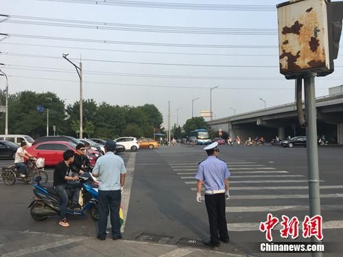 6月21日上午,北京仰山桥下十字路口,执勤人员要求非机动车停在停止线后。 北京启动路口“最严执法” 出狠招整治交通乱象
