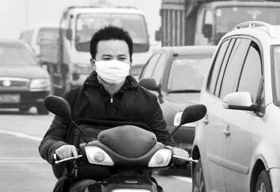 一位长沙市民戴着口罩在灰霾中骑行。