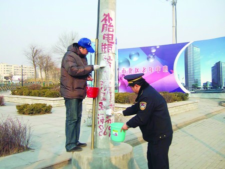 志愿者配合城管清理小广告