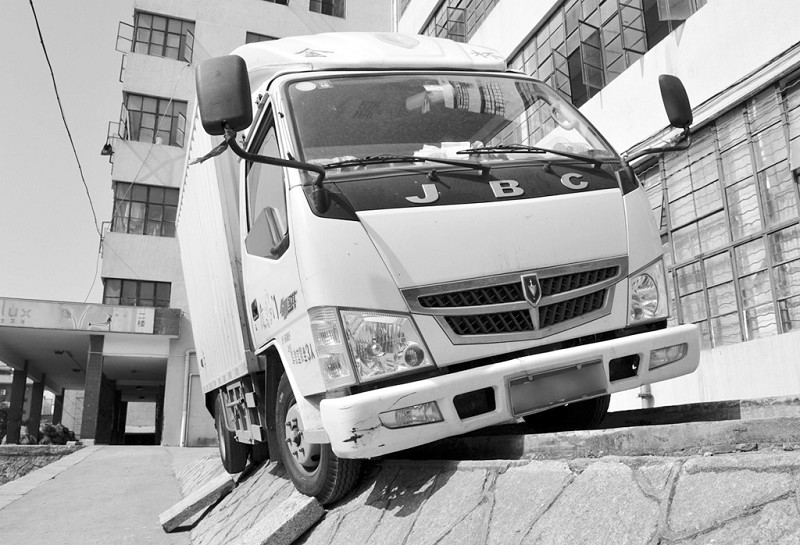 小货车卡在约一米高的台阶上,摇摇欲坠