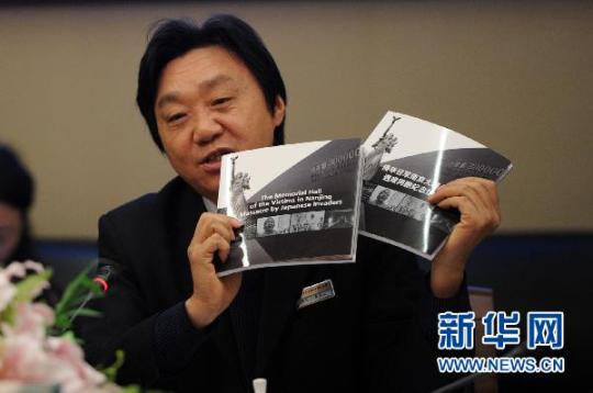 12月12日，侵华日军南京大屠杀遇难同胞纪念馆馆长朱成山正在展示新书《侵华日军南京大屠杀遇难同胞纪念馆概览》。 新华社记者 韩瑜庆 摄