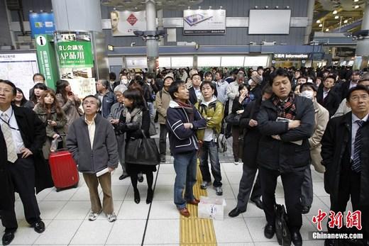 日本近海3月11日发生了强烈地震，首都东京震感强烈。日本气象厅随即发布了海啸警报，称地震将引发约6米高海啸。图为日本品川站受强震影响停运，旅客在车站内实时关注最新地震情况。