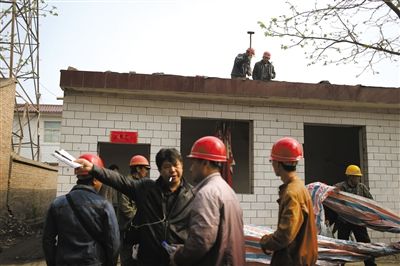 拆迁公司负责人指挥工人拆除搬迁完毕的房屋。