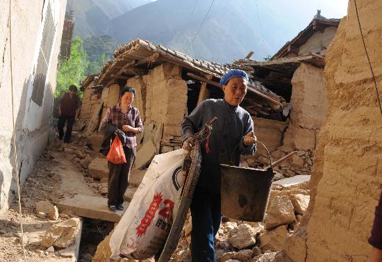 图文:甘肃陇南村民从震坏的房屋内转移生活用