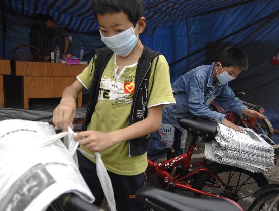 图文:两名小学生将报纸捆绑在自行车上