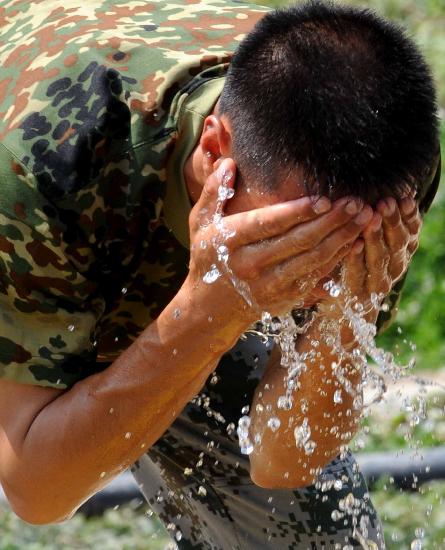 图文:一位军官在用冷水洗脸降温
