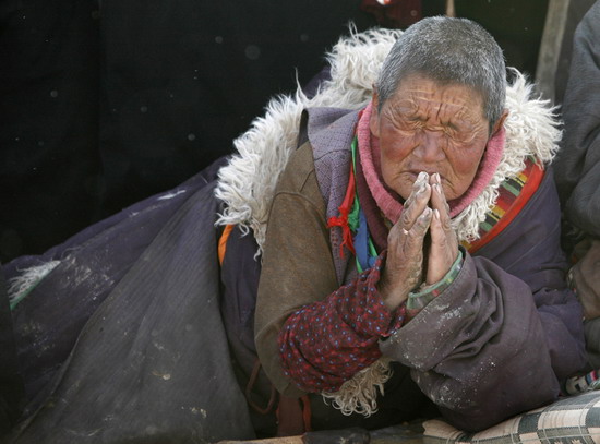 2008年2月19日,在四川阿坝,一个藏族妇女正在揭开唐卡的仪式上祈祷.