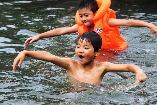 孩子们在湖南湘西凤凰古城沱江上戏水,躲避酷热天气.
