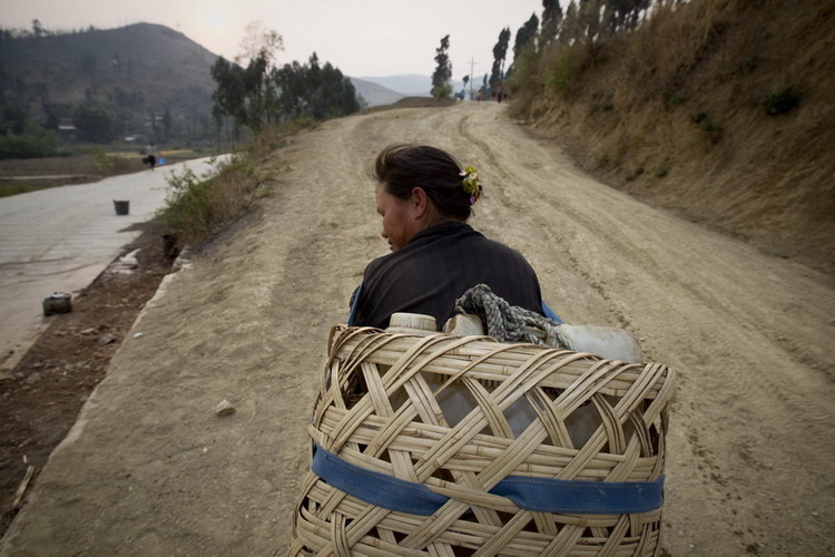 图文：农妇取水后走在回家的土坡上