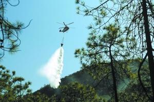 直升机悬挂水桶投水灭火。 东方IC供图
