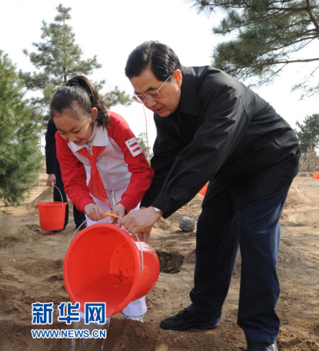 这是胡锦涛同少先队员一起给刚栽下的树苗浇水。新华社记者李学仁摄