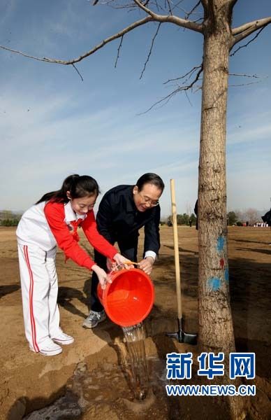 这是温家宝同少先队员一起给树浇水。新华社记者姚大伟摄
