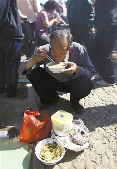 5日,西小营村,一村民就着自带的咸菜喝粥.新京报记者 浦峰 摄