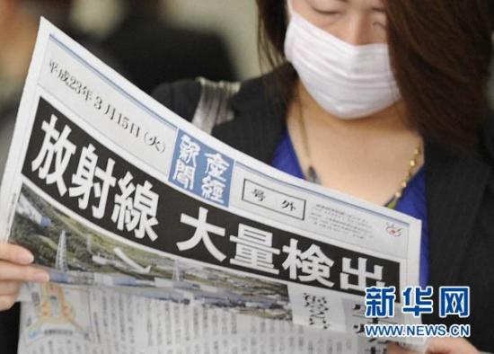 3月15日，在日本大阪，一名女士观看报纸上关于福岛第一核电站的报道。东京电力公司当日说，福岛第一核电站3号机组反应堆上方有白色蒸汽冒出，4号机组出现爆炸并发生火情。日本首相菅直人指示，居民避难半径从第一核电站周边20公里扩至30公里。新华社/共同社