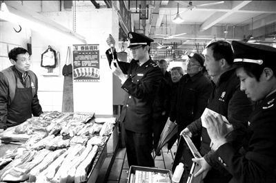 13日，上海市金山区工商分局食品科的工作人员对市场出售的猪肉进行快速抽检。新华社发 