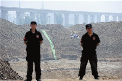 因为盗采沙，河道被挖出了巨坑，工作人员在坑边豁口处防范不法者再来。