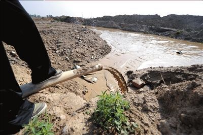 不知从何处而来的污水通过一根管道源源不断地排入河道。