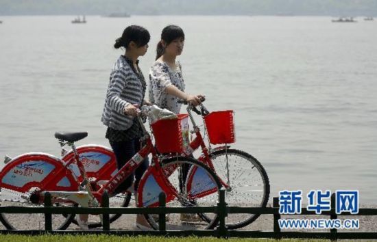 游客推着公共自行车逛西湖。2008年5月1日 新华社发 朱引炜 摄