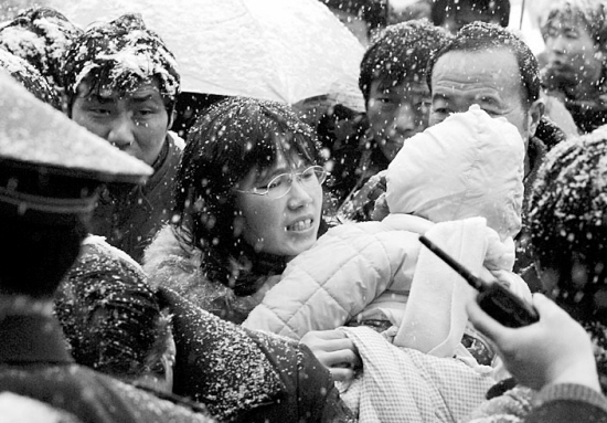 1月27日,一位怀抱小孩的旅客顶着大雪在合肥火车站进站候车.