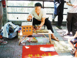 女子抱着一只鸡在马路边摆摊算命骗人.