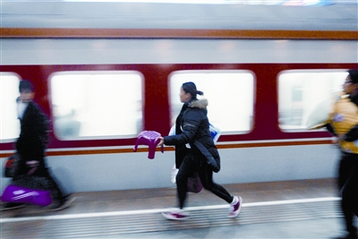 图为昨晚,在武昌火车站,一位旅客拿着小板凳匆忙赶火车.