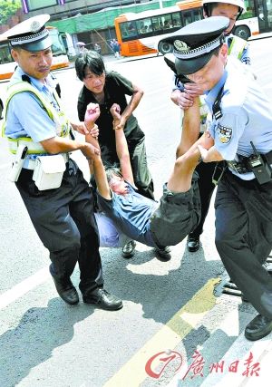 警察将拦车倒地不起的女子抬走.