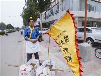 "市民张先生拨打本报新闻热线称他看到了"武大郎,说他举着一个印有"