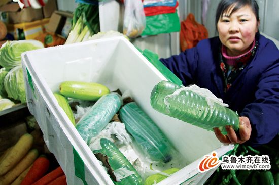 2月13日，在青年路农贸市场，卖菜人梁秀英展示蔬菜包装箱内装的水瓶。（记者 丁瑜 摄）