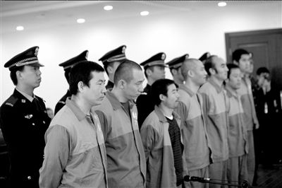 马斌（前排左一）等7名嫌疑人出庭受审。本报记者欧阳晓菲摄
