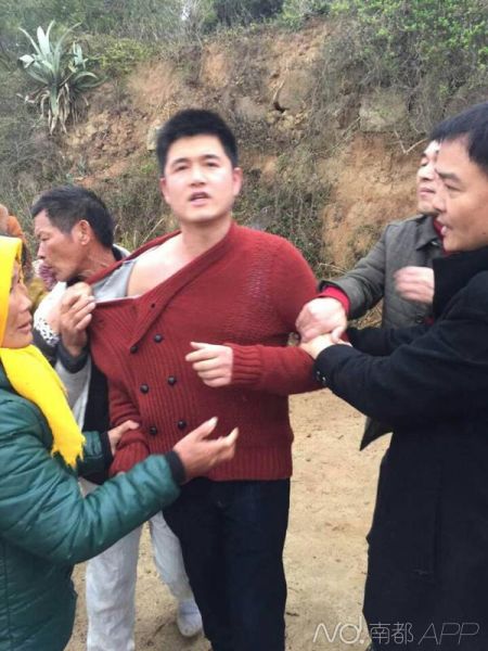 事发后,一名打人者(中间红衣者)被村民围住。 死者家属供图 事发后,一名打人者(中间红衣者)被村民围住。 死者家属供图