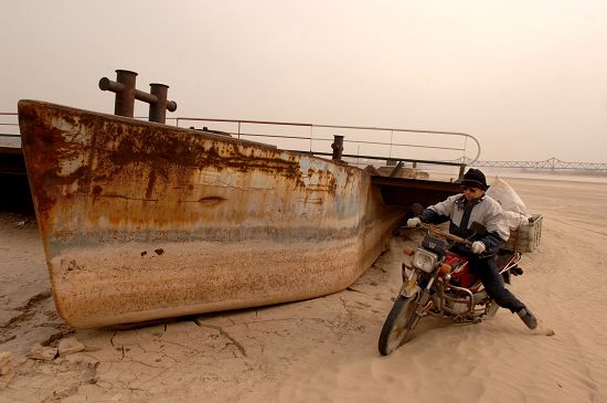 一位农民骑车从黄河山东济南段裸露的河床上经过。 