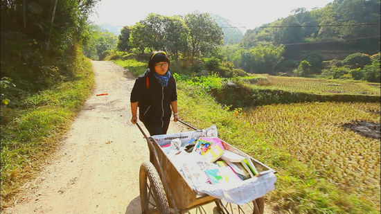 　山路不通车辆，在广西桂林支教的汤玲玲用平板车将书推到学校。
