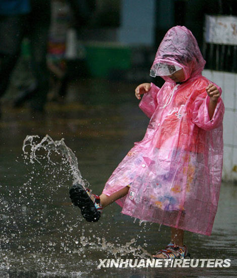 图文:一个孩子在被雨水浸没的街道上玩耍