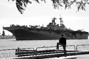 2日，一名埃及男子看着一艘美军两栖攻击舰经过苏伊士运河。该战舰和另一艘同类型战舰同日抵达临近利比亚的地中海。