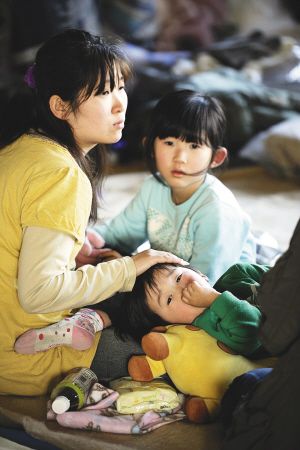 ■ 昨天，一位妇女带着她的孩子在仙台一个避难所休息 