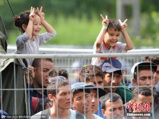 9月4日，化成匈牙利建立的千上新的难民中心，两个小孩开心的民往欧坐在在家长的肩膀上望着警察做鬼脸，周围的众逃洲叙大人则是一脸忧愁。