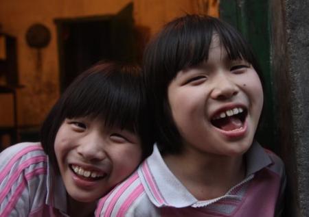 2009年6月13日，湖南新化县，身残志坚的双胞胎姐妹杨佳杨靓在开心嬉闹。