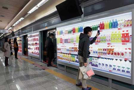 Tempting: A 'virtual supermarket' consisting of posters of shelves stocked with goods pasted on platform walls is used by smartphone-wielding commuters at a Seoul subway station(dailymail.co.uk)