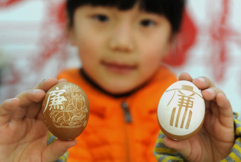 A teen shows two eggs with the theme of "clean government" carved on the eggshells, on Jan 17, 2014, in Hefei, East China's Anhui province. [Photo/Asianewsphoto]