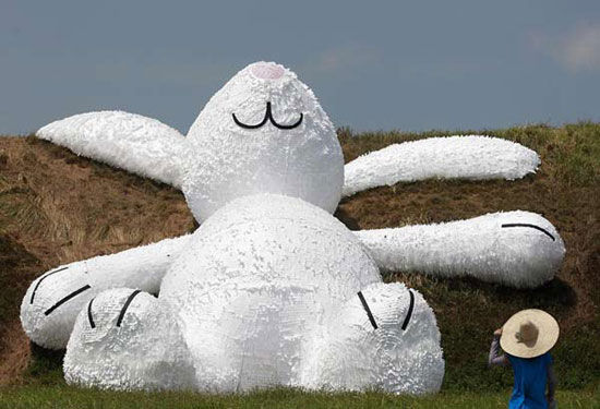 A person stands in front of a 25.3-meter-long giant rabbit designed by Dutch artist Florentijn Hofman at an old aircraft hangar as part of the Taoyuan Land Art Festival in Taoyuan, northern Taiwan, Sept 3, 2014. [Photo/Agencies]