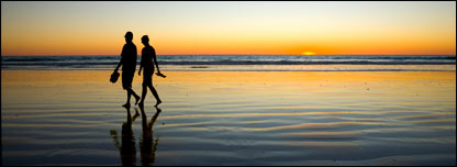 A couple walking on a beach at sunset